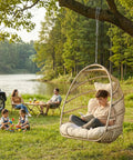 Boy relaxing in Outdoor Egg Chair Without Stand With 350 Lb Capacity, Foldable Rattan Swing Cushioned Basket Seat under tree by lake