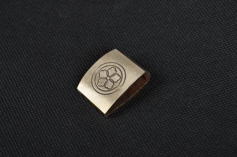 Dope Brass Habaki Collar Clip For Katana And Japanese Swords with engraved floral design, shown on textured surface
