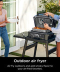 Couple using Woodfire Pro Connect Deluxe XL Backyard Grill and Smoker With Bluetooth App Control on patio