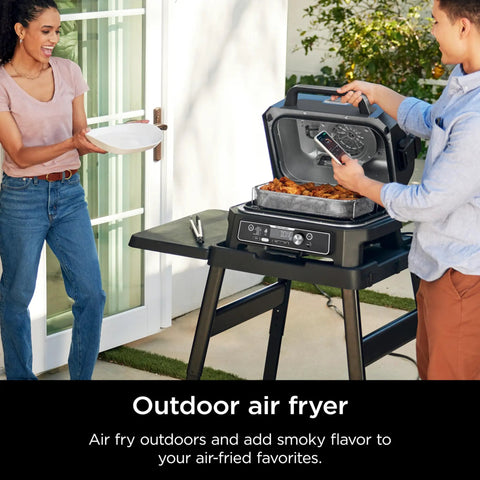 Couple using Woodfire Pro Connect Deluxe XL Backyard Grill and Smoker With Bluetooth App Control on patio