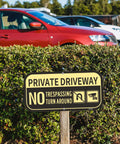 Two-pack Ashoaza private driveway signs, aluminum, 12 x 6 inches, installed on a wooden stake in front of a hedge.