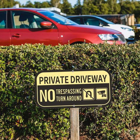 Two-pack Ashoaza private driveway signs, aluminum, 12 x 6 inches, installed on a wooden stake in front of a hedge.