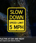 6 Pack Bright Yellow Slow Down 5 MPH Speed Limit Signs on tree, reflective aluminum, 16.5x12in, used for street safety.
