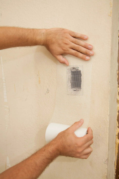 Applying Onetime Fiber Mesh Crack Patch Wall Repair Fabric 6 Inch By 75 Foot Self Adhesive to wall.