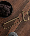 Champagne Bronze Cabinet Pulls With Center Hole 5 Inch Length Modern Zinc Finger Handles for drawers and cupboards on a wooden surface