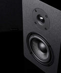 Close-up of PB42X Powered Bookshelf Speakers With 30 Watt RMS, showing carbon fiber woofer and silk dome tweeter, black finish.