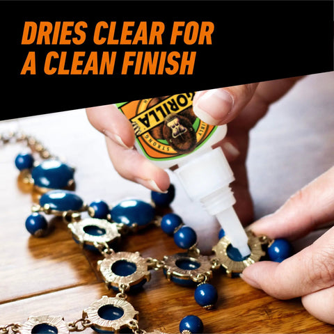 Applying Rock Solid Super Glue Gel No Drip Formula for jewelry repair with blue beads on a wooden surface.