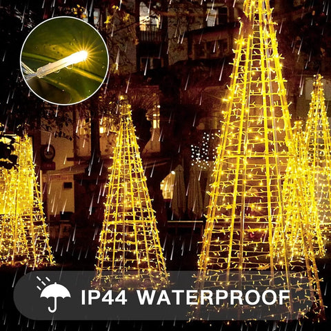 Outdoor display of Indoor String Lights With Remote 33ft 100 LED Warm White Twinkle Fairy Lights illuminating conical trees.