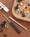 Heavy Duty Brass Screw Back Purse Feet And Metal Rivets For Handbag Bottom Protectors With Punch And Screwdriver Included No Sweat Install For DIY Leather Craft Gear tools and accessories on brown leather surface