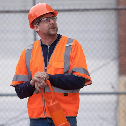 Man wearing High Visibility Sleeved Mesh Safety Vest With Brilliant Reflective Tape And Utility Pockets Class 3 at job site.