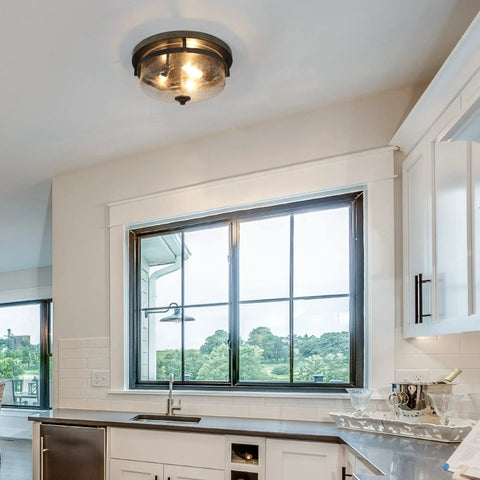 Farmhouse Flush Mount Ceiling Light With Faux Wood Finish And Seeded Glass Shade in a kitchen setting over a window.