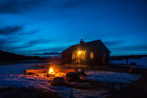 Log cabin illuminated at dusk with snow, showcasing ambience with LED Bug Light A19 Replaces 100W Incandescent, Amber Yellow Spectrum.