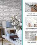 Living room featuring installed 3D Faux Brick Peel And Stick Tiles Set Of 10 Small 11.8 By 11.8 Inch PVC Wall Panels In Warm White.
