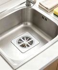 Hair Drain Stickers Disposable Hair Catcher for Shower Drain in shiny stainless steel sink with hair trapped.