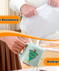 Woman showcasing Pro Grade Clear Vinyl Sticker Paper's tear resistance while pouring water on a decorated mug.