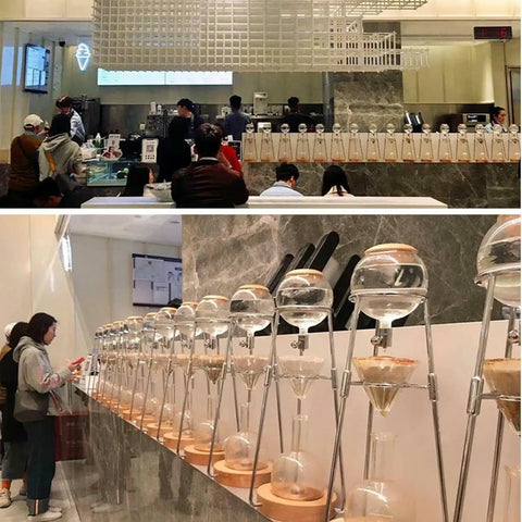 Skip The Coffee Shop Line With This Adjustable Cold Brew Drip Tower Featuring A Precision Flow Valve And Durable Heat Resistant Stainless Rack For Silky Homemade Sips displayed in a busy cafe.
