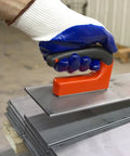 Side view of Master Magnetics strong magnet with ergonomic orange handle pressed onto steel sheets.