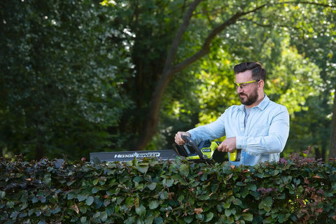 Pro Level 18V ONE PLUS Cordless Hedge Trimmer Featuring 55cm Double Edge Blades in use by a man trimming hedges.