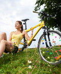 Yellow bike with 210 Glow In The Dark Bike Spoke Beads Set Colorful Plastic Spoke Clips For Bicycle Wheels beside woman outdoors.
