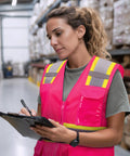 Top Level High Visibility Safety Vest With Bold Reflective Strips And Plenty Of Gear Pockets For Daily Grind, worn by woman in warehouse.