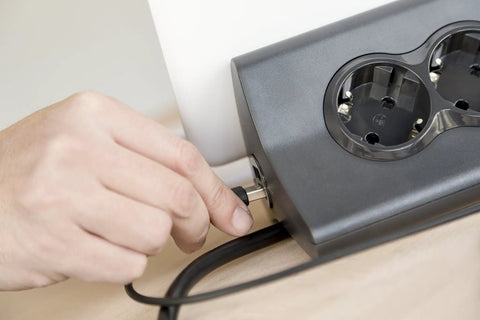 Kickstart Your Workspace Game With This Solid Three Outlet Power Strip And Dual Usb Charging Station with hand plugging in cord.