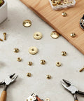 12 Pcs Brass Clock Hand Nut Assortment Set With 5mm 6mm 10mm OD scattered on table with tools and hardware