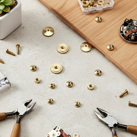 12 Pcs Brass Clock Hand Nut Assortment Set With 5mm 6mm 10mm OD scattered on table with tools and hardware
