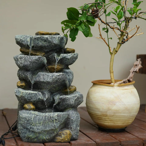 Solar Water Fountain Outdoor Garden 19.3 Inch Cascading Stone Design Five Tier Rock Feature Waterfalls beside potted plant