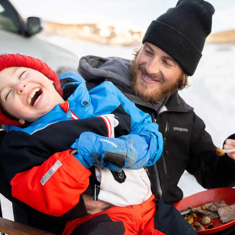 A person in winter clothing laughing, sharing a joyful moment during a snowy outdoor setting, focusing on warmth and connection.