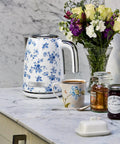 Floral electric kettle on marble counter with tea accessories and flowers