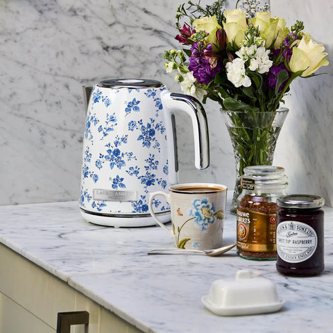 Floral electric kettle on marble counter with tea accessories and flowers