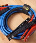 Coiled blue jumper cable with red and black clamps secured by Wrap-It strap for the Garage Organization Value Pack With Assorted Storage Straps For Cords And Hoses Cable Management Essentials For Ropes And Gear Easy Tie Downs And Quick Access To Keep Your Space Neat.