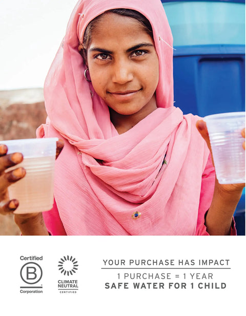 A person in a pink scarf holding two cups of water, standing in front of a blue container. Text: Safe water for children impact statement.