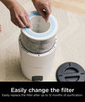 Hands replacing filter on HP100 series air purifier, using Replacement Air Purifier Filter With Anti Allergen HEPA And Odor Lock.