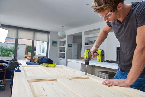 High Output 18V Cordless Drill Driver With 22 Torque Settings And Self Tightening Chuck, Includes 2.0Ah And 4.0Ah Lithium Batteries in use on wooden door.