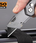 50 Pack Utility Knife Blades With Blackened SK-5 Steel cutting through black material, close-up on box cutter knife.
