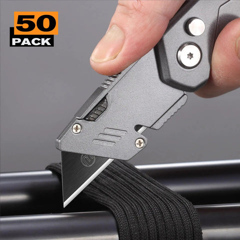 50 Pack Utility Knife Blades With Blackened SK-5 Steel cutting through black material, close-up on box cutter knife.