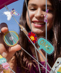Kid smiling while attaching Totally Adorable Kids Bike Spoke Decorations Set With 36 Colorful Charms Featuring Dino, Flower And Butterfly Themes