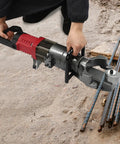 person using 1150W Hydraulic Electric Rebar Bender to bend 4-25mm steel rods on construction site, showing precise handling.