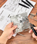 Hands using 12 Piece Metal Model Tool Set For DIY 3D Puzzles Includes Long Edge Bending Tools Tab Twisting Tool Cone Bend Aids Clipper And Four Metal Tweezers For Precise Assembly with metal sheet and instructions on wooden table.