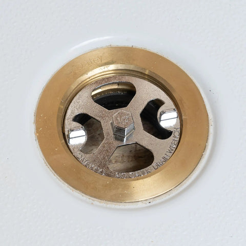 Close-up of No Calk Shower Drain Wrench with brass and plastic construction and stainless steel core in drain