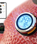 Universal Smart Grill Gauge Thermometer Hub With Wi Fi And Bluetooth For Kamado Joe Weber Grills And Smokers Replacement Accessory 3.5 Inch Length 0.3 Inch Diameter Not For Big Green Egg For Grill Lovers Who Want Pro Level Monitoring On The Fly shown on Kamado Joe with smartphone and smartwatch displaying temperatures.
