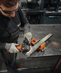User operating the Top Shelf 1400 Watt Angle Grinder Packs Knock Tough 125mm cutting muscle on metal workpiece.
