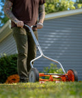 Man using 1204-14 14-Inch 4-Blade Push Reel Lawn Mower With Lightweight 19-Pound Body 8.5-Inch Polymer Wheels Red Finish in backyard.