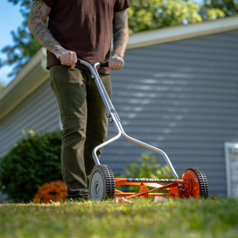 Man using 1204-14 14-Inch 4-Blade Push Reel Lawn Mower With Lightweight 19-Pound Body 8.5-Inch Polymer Wheels Red Finish in backyard.