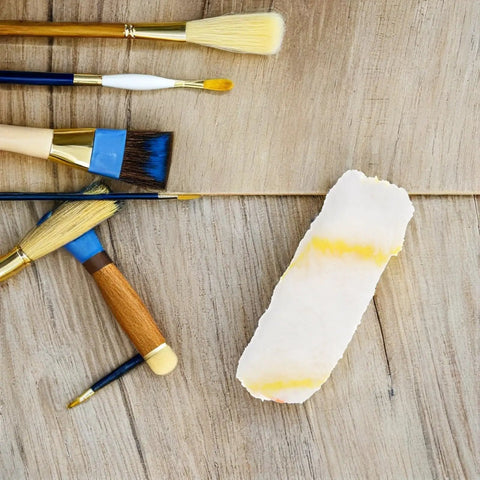 Heavy Duty Polyester Paint Roller Cover Refills on a wooden surface alongside various paint brushes, ideal for painting projects.