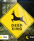 Deer Xing Crossing Sign 12x12, 2 Pack, Engineer Grade Reflective Aluminum, Built Tough Weather Resistant High Visibility Safety Sign for Driveways, Rural Roads, and Deer Rich Areas. Yellow deer crossing sign on chain-link fence, day and night