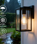 Exterior Wall Lantern Outdoor Sconce For Porch And Patio Lighting with black finish, illuminated at night in rainy weather