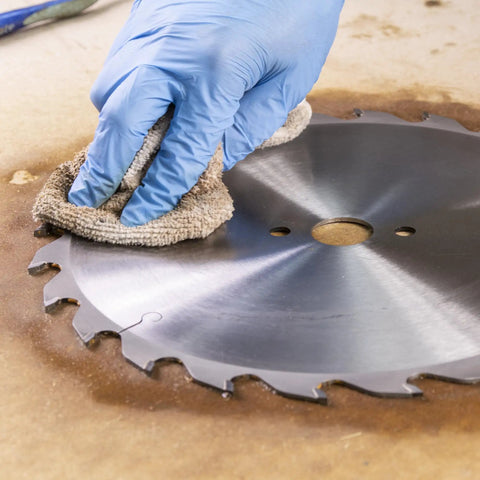 Hand cleaning circular saw blade with Blade And Bit Cleaner For Tools 18 Fl Oz Resin Pitch And Rust Remover Safe Non Toxic Formula For Workshop Tools Keeps Surfaces Clean Without Harsh Scrubbing.