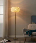 Rowan Brass Floor Lamp With Unique Thread Shade, Free Standing LED Light for modern living room decor beside gray armchair.